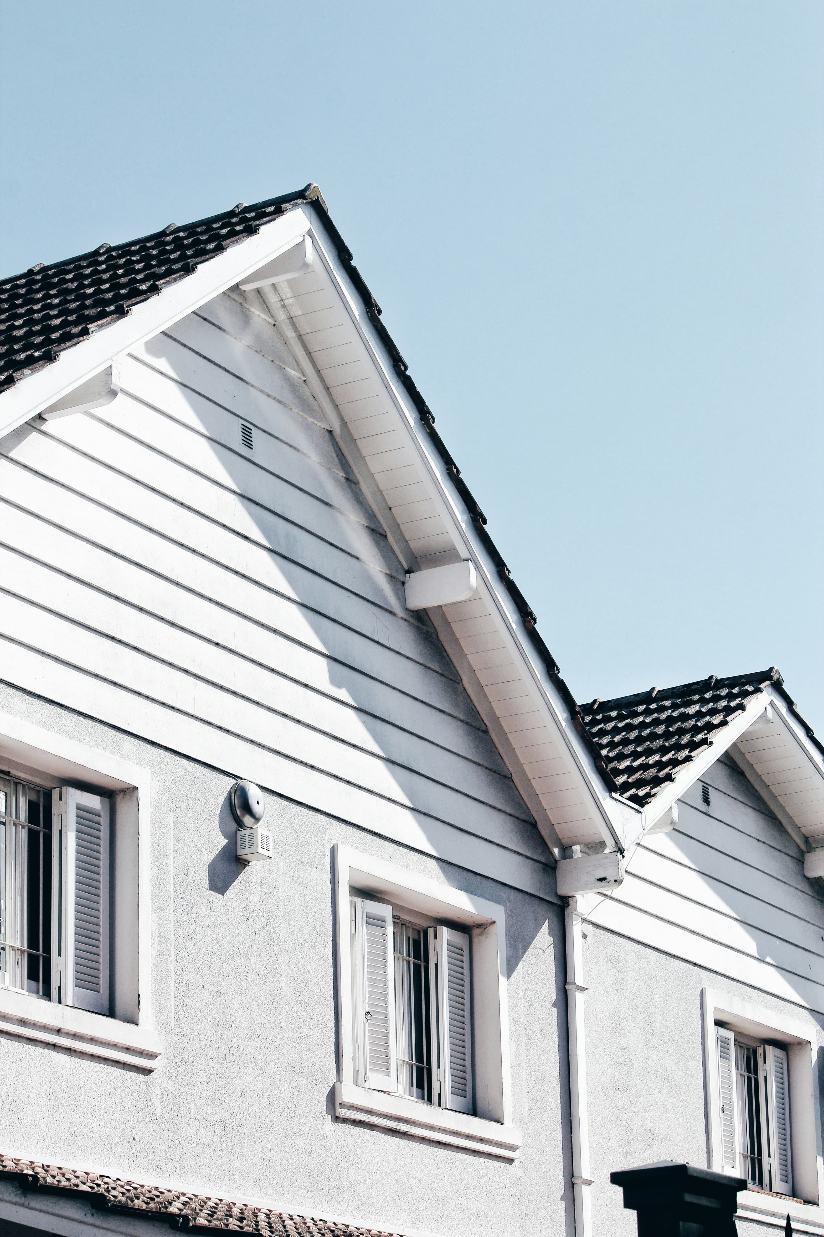 The white gables of a house against a clear blue sky.