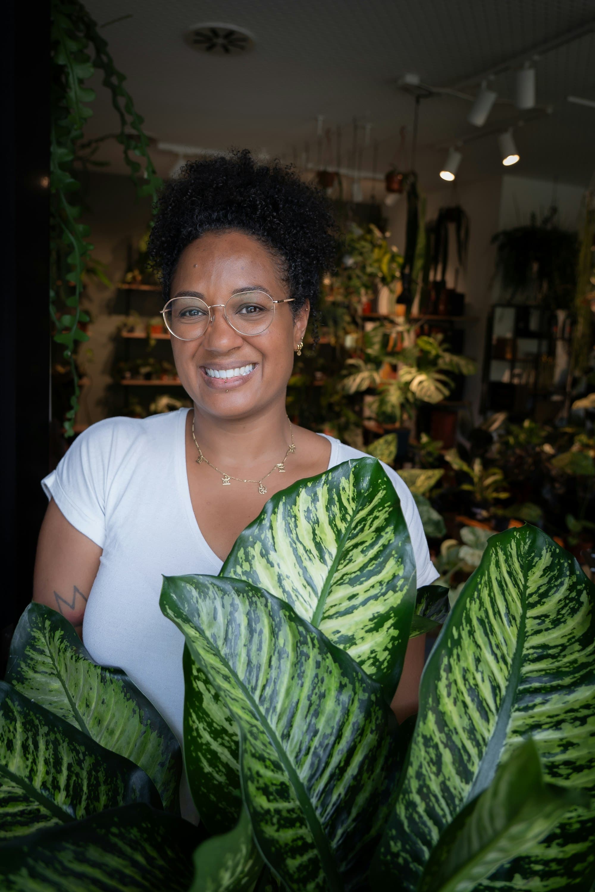 A shop owner smiling, holding a plant.